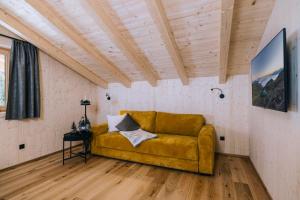 a yellow couch in a room with a wooden ceiling at Moidi's Chalet Spieljoch in Fügenberg