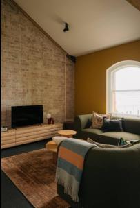 a living room with a couch and a flat screen tv at Gibson Mill Penthouse with private balcony - 301 in Hobart