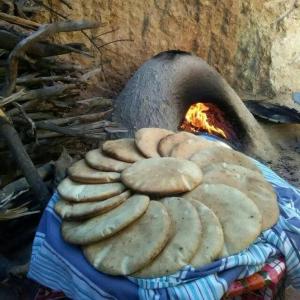Un montón de pan sobre una manta al lado de un horno. en Auberge panorama, en Kasba des Aït Athmane