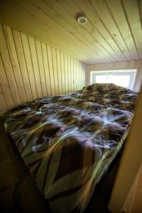 a bed in a room with a wooden wall at Holiday cabin 'OAK' in Salacgrīva +15 photos