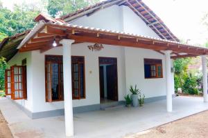 een klein wit huis met een houten dak bij Nadi Villa Midigama in Midigama East