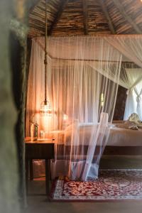 a bedroom with a canopy bed with a table at Mtoni River Lodge in Arusha