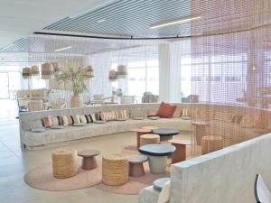 a lobby with a couch and tables and chairs at Canvas Sevilla Lago in Seville