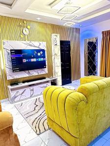 sala de estar con sofá amarillo y TV en Kunbiz Apartments, en Murtala Muhammed International Airport