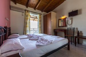 a bedroom with two beds and a table and a window at Vossos Hotel Apartments in Laganas