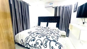 1 dormitorio con cama y cortinas en blanco y negro en Kunbiz Apartments, en Murtala Muhammed International Airport
