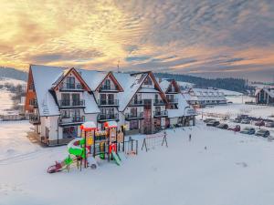 a ski lodge in the snow with a playground at Malinowy Potok in Białka Tatrzanska