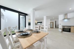 a dining room and living room with a table and chairs at Luxury White House Apartment in Puerto Calero