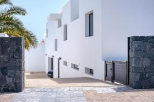 a white building with a palm tree in front of it at Luxury White House Apartment in Puerto Calero