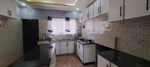 a large kitchen with white cabinets and a sink at Ashton cosy homes in Nakuru