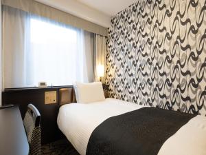 a hotel room with a bed and a window at APA Hotel Komatsu in Komatsu