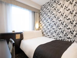 a bedroom with a bed with a black and white patterned wall at APA Hotel Komatsu in Komatsu