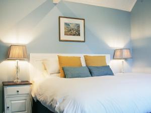 een slaapkamer met een bed met blauwe muren en 2 lampen bij Valley Farm Cottage in Sudbourne