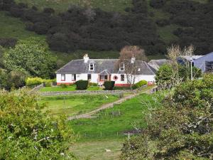 a white house on a hill with a green yard at Kilpatrick Farm House in Pinmore