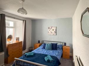 a bedroom with a bed with blue sheets and a mirror at Kilpatrick Farm House in Pinmore +6 photos