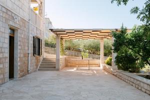 a wooden pergola on a building with a bench at Large and charming apartment near beach with big & sunny terrace in Sumartin