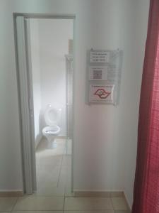 een badkamer met een toilet en een bord aan de muur bij Suite Airport in Campinas