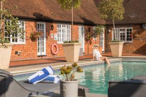 eine Frau, die am Rand eines Schwimmbeckens sitzt in der Unterkunft Weston Cottage 4 in Send + 17 Fotos