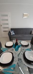 a glass table with plates and wine glasses on it at Good Place Kodowa in Skorka
