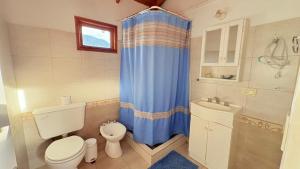 a bathroom with a toilet and a blue shower curtain at Los Saucos in El Hoyo