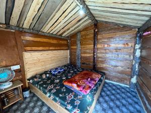 un lit vide dans une cabane en bois avec un ventilateur dans l'établissement Hill View Cottage, à Chakrata
