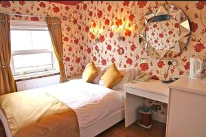 a bedroom with a bed and a desk and a mirror at Crompton Guest House in Hounslow