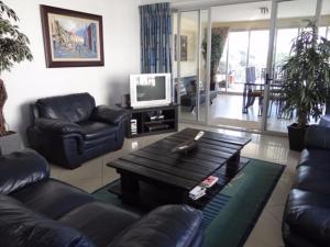 Una sala de estar con un sofá, una mesa y un televisor. en Arabella No. 4, en Margate