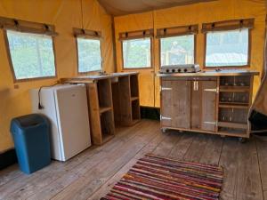 Una cocina en una tienda de campaña con refrigerador y ventanas. en Camping le Faulion, en Cuzy 11 fotos más