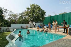 a group of people sitting in a swimming pool at EKO STAY - Solace Villa I Charming Villa close to Candolim Beach in Candolim
