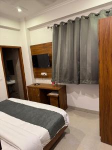a bedroom with a bed and a desk with a television at The Namami Tapovan in Rishīkesh