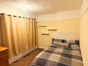 a bedroom with a bed with a plaid blanket at Warn Cossy Luxe Room in Addington +2 photos