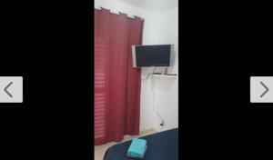 een kamer met een rood gordijn en een tv bij Suite Airport in Campinas