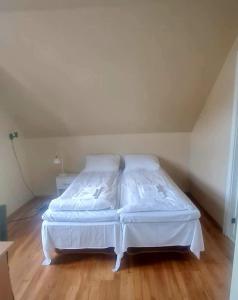 un letto bianco in una camera con pavimenti in legno di Sauda Bed & Breakfast a Sauda
