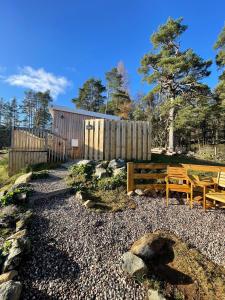 a backyard with two benches and a wooden fence at Kaoglen - Alpine Pod - Hot Tub - Cairngorms - Pitlochry in Kirkmichael