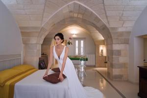 Eine Frau in einem weißen Kleid auf einem Bett in der Unterkunft Mille908 in Muro Leccese