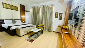 a hotel room with a bed and a couch and a tv at Hotel Four Season - Gomtinagar - Lucknow in Lucknow +17 photos