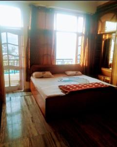 a bedroom with a large bed with two windows at Harmony Homestay in Solan