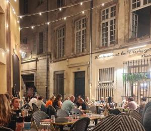 a group of people sitting at tables in front of a building at Studio lumineux Avignon centre, proche de tout in Avignon