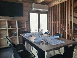 Bali domy RESTORT & SPA في Laskowa: طاولة خشبية عليها كراسي واكواب للنبيذ