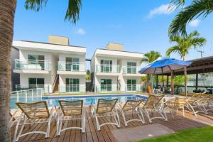 um grupo de cadeiras e um guarda-sol ao lado de uma piscina em Pousada Oásis Tropical em Porto de Galinhas