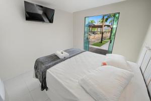 um quarto branco com uma cama e uma tv em Pousada Oásis Tropical em Porto de Galinhas