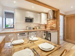 a kitchen with a wooden table with plates and wine glasses at The Hayloft-Uk34015 in Godshill