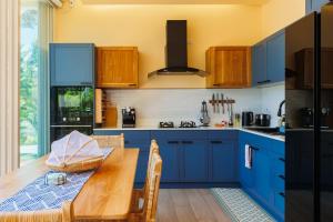 een keuken met blauwe kasten en een houten tafel bij Luxury Villa - Pool - Gym - Steam Room - Garden in Ko Pha Ngan