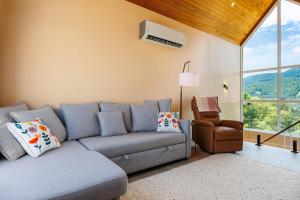 een woonkamer met een grijze bank en een stoel bij Luxury Villa - Pool - Gym - Steam Room - Garden in Ko Pha Ngan