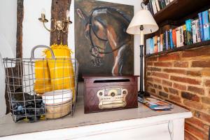 een tafel met een lamp en een schilderij van een paard aan de muur bij 3 Tudor Cottages in Long Melford