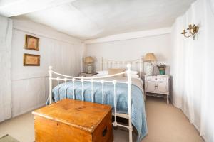 een slaapkamer met een wit bed en een houten kofferbak bij 3 Tudor Cottages in Long Melford