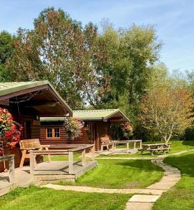 a log cabin with picnic tables in the grass at Wall Eden Farm - Luxury Log Cabins and Glamping in Highbridge