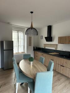 a kitchen with a wooden table and blue chairs at La maison du viaduc in Chauvigny