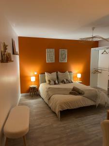 a bedroom with a large bed with an orange wall at La maison du viaduc in Chauvigny