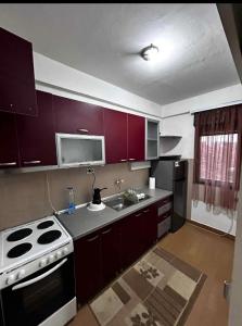 a kitchen with purple cabinets and a stove and a sink at M comfort in Kumanovo